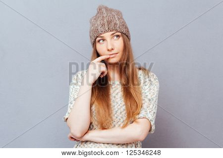 Thoughtful stylish woman looking away over gray background