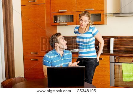 Man watching something on laptop, his wife is angry