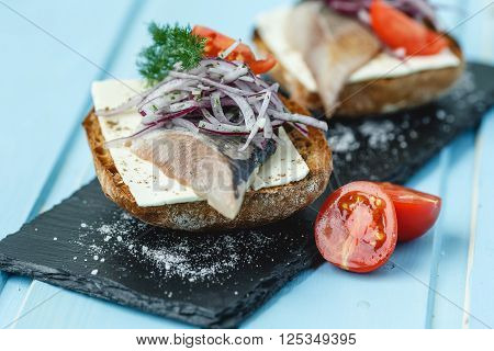 Sandwich with herring and vegetable on blue wood background