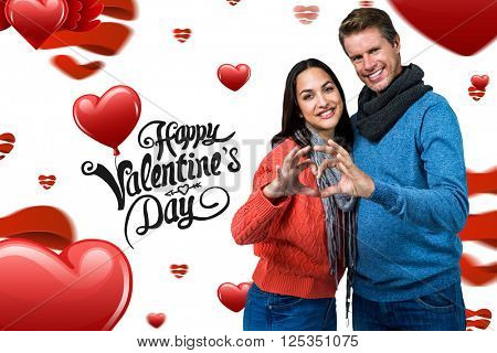 Smiling couple making heart shape with hands against cute valentines message