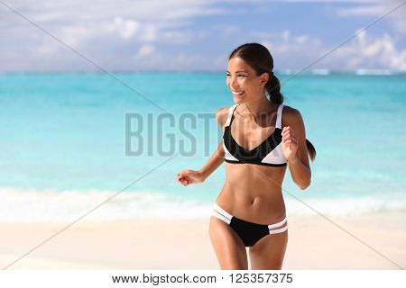 Happy bikini woman having fun on beach holiday on tropical summer travel vacation. Sexy cute Asian girl with slim suntan body running playful sunbathing in sunny Caribbean destination.
