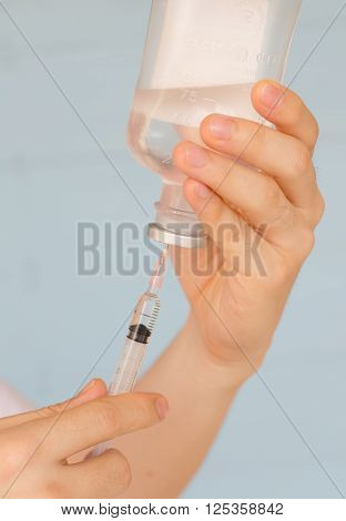 Nurse prepares to draw normal saline from plastic bottle