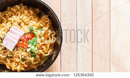 Top view of korean noodles(Ramyun) in black bowl on wooden table.