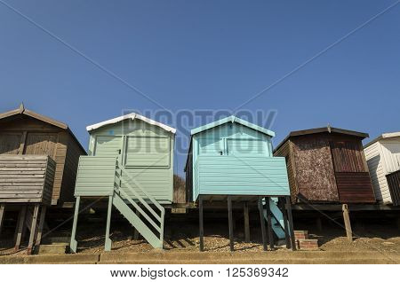 A row of colourful beach huts under a blue sky at Frinton-on-sea, Essex England UK.
