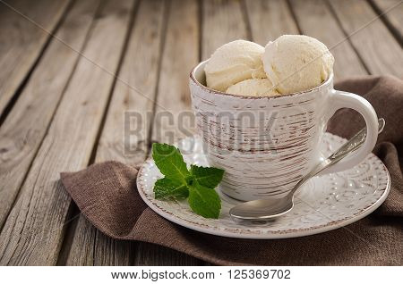 Vanilla ice cream in cup on rustic wooden background, selective focus, copy space