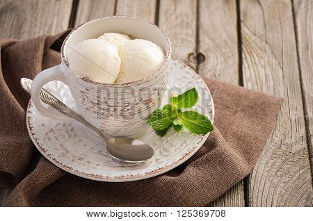 Vanilla ice cream in cup on rustic wooden background, selective focus, copy space
