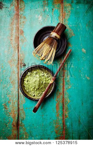 Organic matcha tea and a bamboo tea whisk on a rustic background