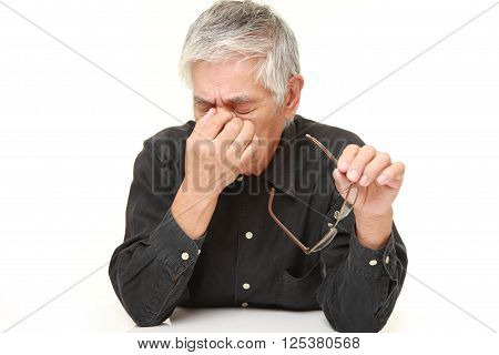 portrait of senior Japanese man suffers from Asthenopia