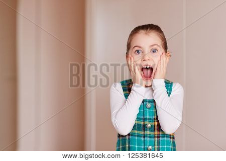 A cute little girl gasping at the camera inside white room