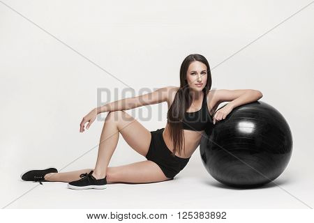 Portrait of young attractive woman doing exercises. Brunette with fit body exercising with fitness ball. Series of exercise poses.