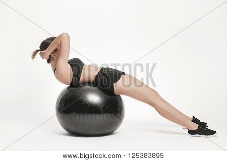 Portrait of young attractive woman doing exercises. Brunette with fit body exercising with fitness ball. Series of exercise poses.