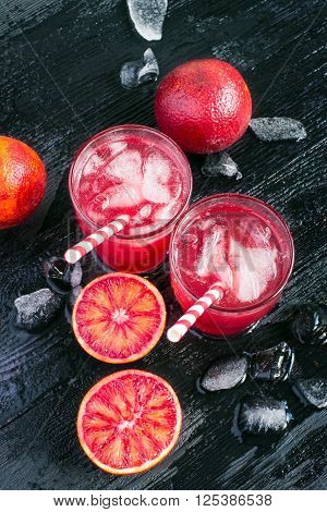 Juice of blood orange fruit halves and ice top view