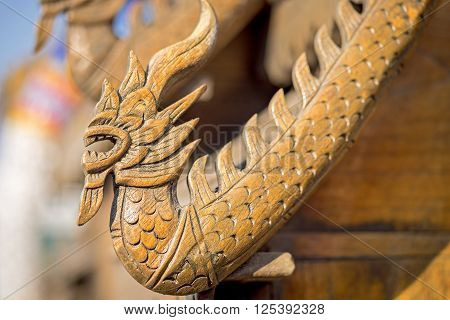 Wooden dragon figure on a small temple roof in Thailand