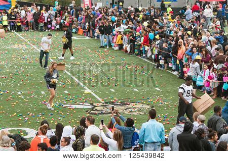 MARIETTA, GA - MARCH 2016: Teen volunteers cover a high school football field with plastic easter eggs and candy as hundreds of local residents wait to begin a massive community easter egg hunt in Marietta, GA on March 26 2016.