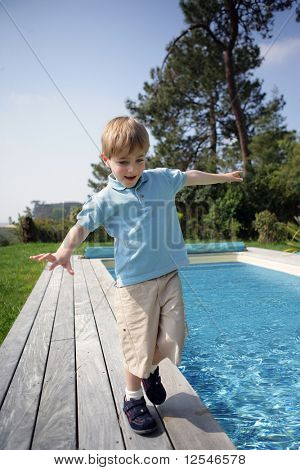 Portræt af en lille dreng gå ved siden af en pool