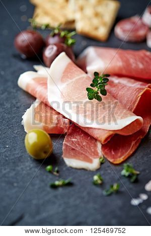 Serano ham with olives on a slate
