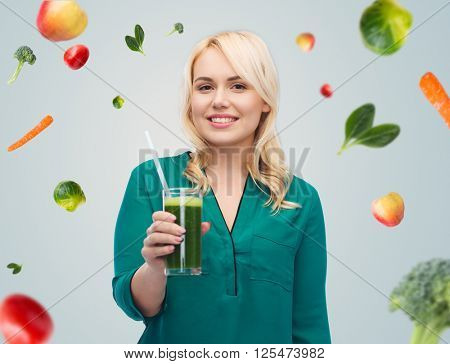 healthy eating, vegetarian food, diet, detox and people concept - smiling young woman drinking green vegetable juice or smoothie from glass over blue sky and clouds background