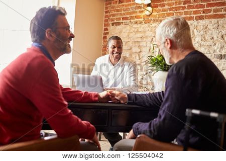 A gay male couple holding hands at a hotel check in desk