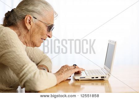 Starsza kobieta pisania na laptopa