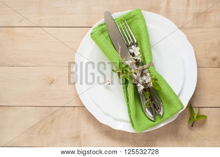 Spring table place setting with white plates cutlery napkin and flowers.