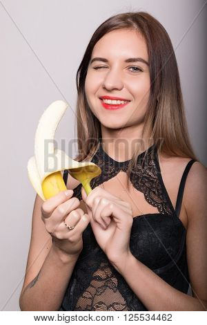 Young amazed woman in lacy lingerie holding a banana, she is going to eat a banana.