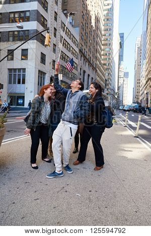 NEW-YORK - CIRCA MARCH 2016: people taking a selfie in New-York. A selfie is a self-portrait photograph, typically taken with acamera phone held in the hand or supported by a selfie stick.