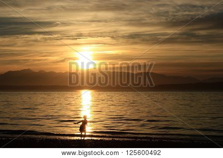 A child plays in the surf at sunset at the beach.