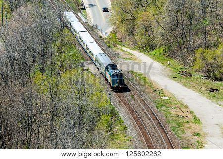 HAMILTON CANADA - MAY 11 2014 - A short VIA Rail passenger train passes through a wooded area. VIA Rail operates Canada's national passenger rail service.