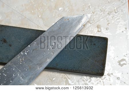 kitchen knife and grindstone on tile floor