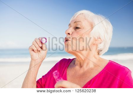 Senior woman making bubbles with a bubble wand on the beach