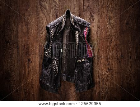 Old-school punk-rock leather jacket hanging on a wooden background