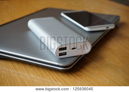 Modern mobile office with metal aluminum devices - cell phone, power bank (external battery) and silver ultrabook (thin portable laptop)