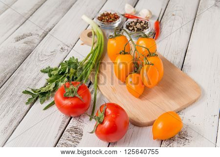 close up of fresh red and yellow delicious tomatoes with greenery on an old wooden background
