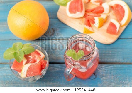 Freshly squeezed orange and grapefruit juice in glass, with fruits on wooden background