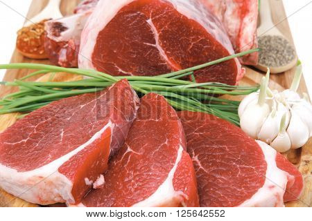 fresh meat : raw uncooked fat lamb pork rib and fillet with green stuff and red chili pepper on wooden plate isolated over white background