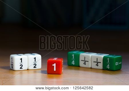 Fraction dices on wood table shown whole and fraction numbers, dark background and selective focus on red dice