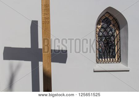 Wooden cross with a years of Saint Missions and its shadow on the wall of the gothic church in Svaty Jur Slovakia. Traditional gothic window beside.