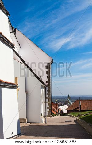 Side part of the gothic christian church built on a hill in village Svaty Jur Slovakia.View on a village and horizon of the nature around. Blue sky with clouds.