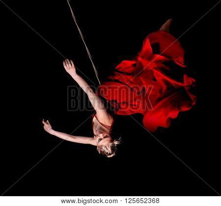 Woman Gymnast In Red Dress On Rope On Black Background