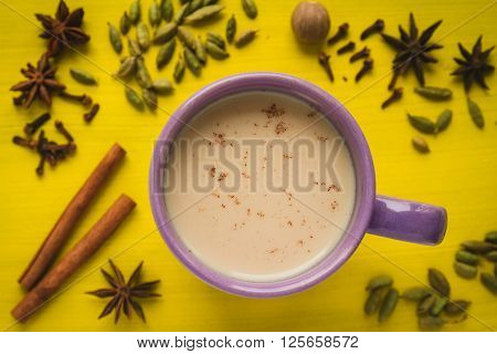 masala chai tea with spices and star Anise cinnamon stick nutmeg and cardamon on the yellow background