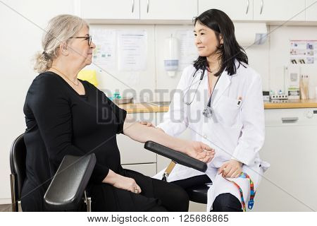 Doctor Touching Senior Patient's Arm Before Blood Test