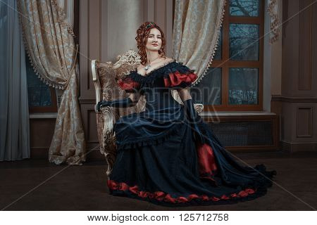 Woman in Victorian dress sitting on a chair in the room.