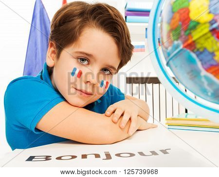 French schoolboy learning geography with the globe at the classroom - bonjour is hello in French