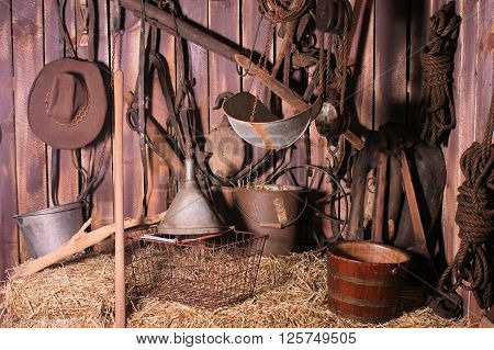 Corner of an old barn filled with antique tools, pails, and pulleys.