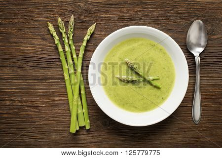 Fresh asparagus soup on wooden background overhead shoot