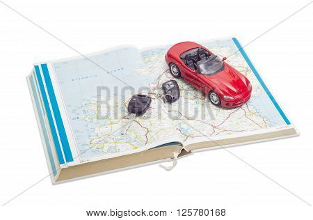 Red toy car cabriolet and car keys on the old open road atlas