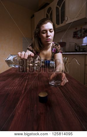 Lonely drunk woman pours alcohol into the glass. Alcoholic addiction.
** Note: Shallow depth of field