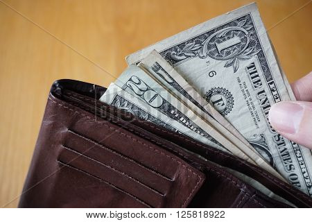 Male hand holding a leather wallet and withdrawing American currency (USD, US Dollars)
** Note: Soft Focus at 100%, best at smaller sizes