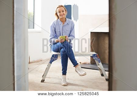 Portrait Of Woman Sitting In Property Being Rennovated