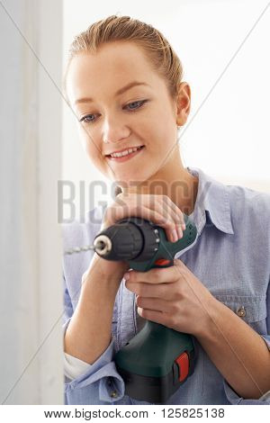 Young Woman Using Electric Drill In House Rennovation Project